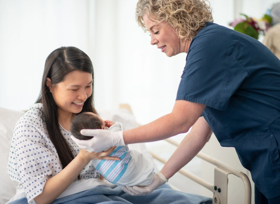 pielęgniarka podająca dziecko kobiecie